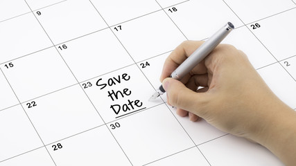 Concept image of calendar with a woman hand writing. Words Save The Date written on calendar to remind you an important appoinment.