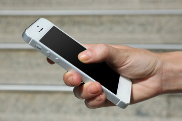 Female hand holding smart mobile phone outdoors