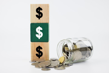 Dollar sign on wooden block with coins in glass jar. Financial concept