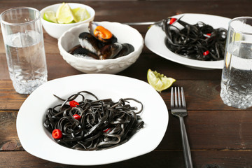Cooked pasta, mussel and lime on brown wooden background