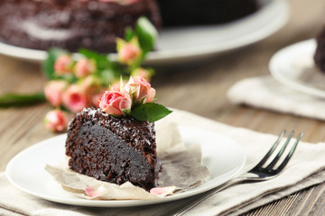 Piece of chocolate cake decorated with flowers on brown wooden table