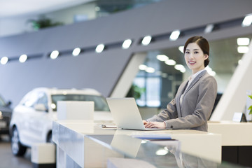 Confident receptionist using laptop at reception counter