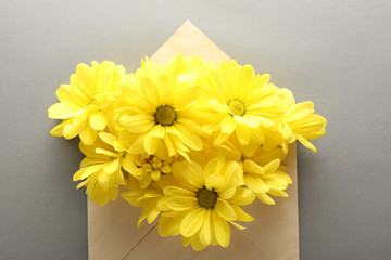 Yellow chrysanthemum in envelope on grey background