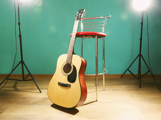 Guitar with bar stool on the floor against blue background in the studio