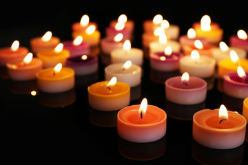 Fototapeta na wymiar Many burning small candles on dark background