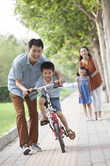Obraz premium Young father teaching his son to ride a bicycle