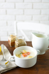 Delicious salmon cream soup on wooden table, which served with sliced lemon and spices