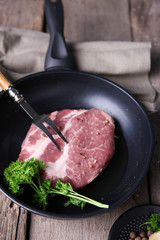 Marbled beef steak on pan and spices on wooden background