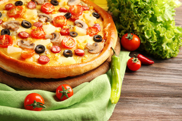Delicious pizza with vegetables and meat on green napkin, close-up