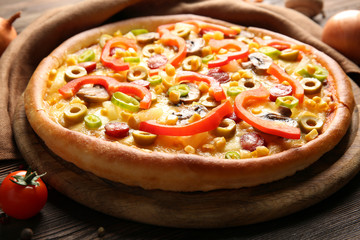 Delicious pizza with vegetables on wooden table