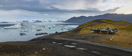 Motorboat in green hill at Jokulsarlon glacial lagoon with ice cube and glacier background