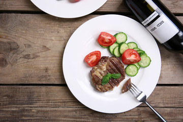 Roasted beef fillet and fresh vegetables on plate, on wooden background