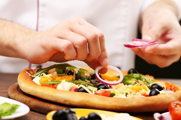 Cook making delicious pizza at the restaurant, close-up