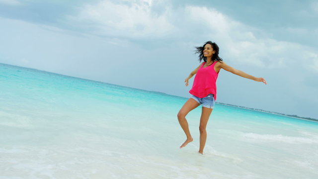 African American girl walking barefoot on ocean sand beach