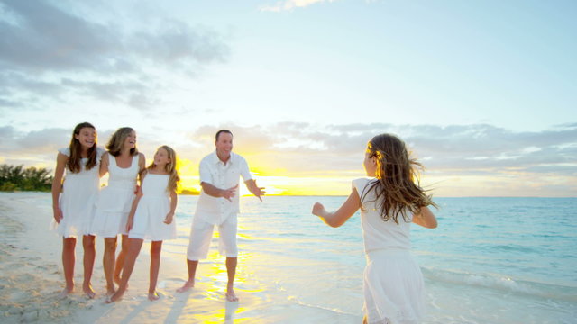Happy Caucasian family enjoying beach vacation at sunset