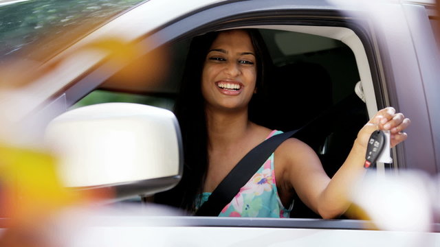 Portrait of confident Asian Indian female smiling holding car key in vehicle