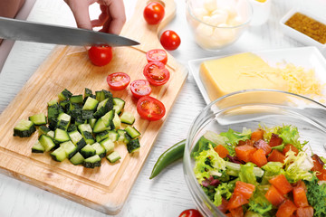 Female hands cutting vegetables for salad, at kitchen