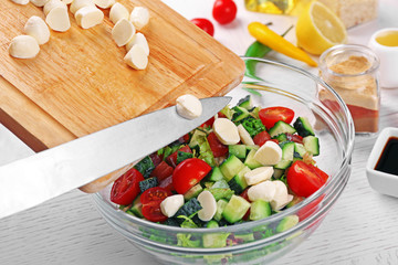 Adding mozzarella cheese to salad, at kitchen