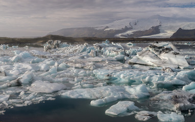 Ice cube and iceberg at Jokulsarlon glacial lagoon with snow mountain background