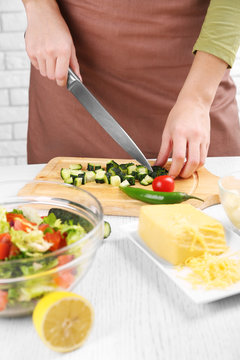 Female hands cutting vegetables for salad, at kitchen