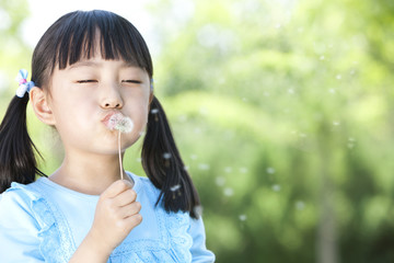 Young Girl Blowing Dandelion