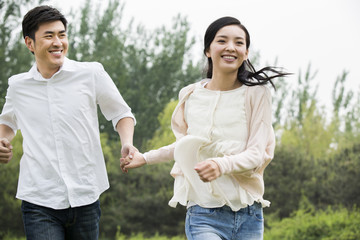 Happy young couple holding hands running
