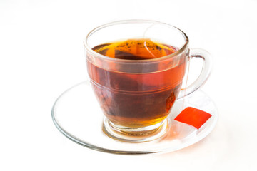 Hot tea with tea bag in transparent cup and saucer