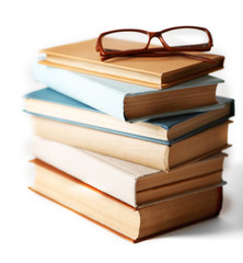 Pile of books and eyeglasses on it isolated on white background