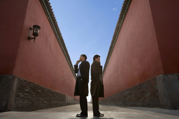 Businessmen Standing Back To Back Next To Building