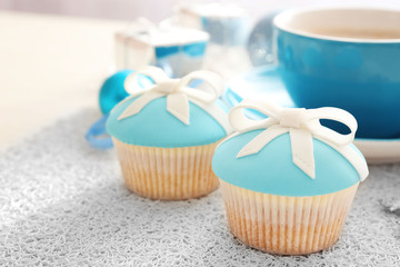 Tasty cupcakes with bow, coffee cup and Christmas toys on color wooden background