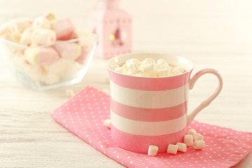 Mug of hot chocolate with marshmallows, on light wooden background