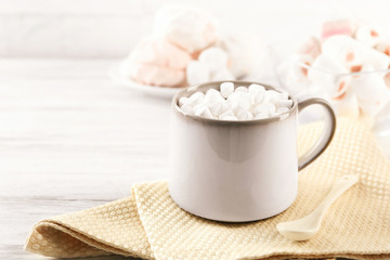 Mug of hot chocolate with marshmallows, on light wooden background
