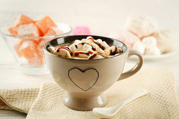Mug of hot chocolate with marshmallows, on light wooden background