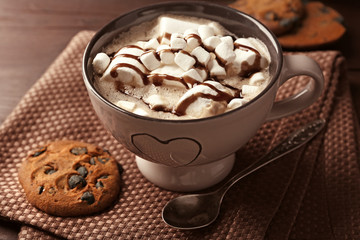 Mug of hot chocolate with marshmallows, on wooden background
