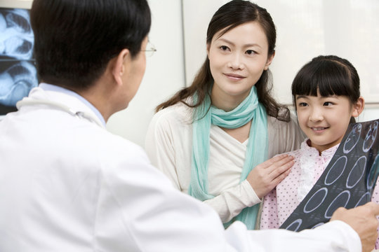 Doctor discussing the results of an MRI scan with a young patient and her mother