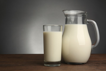 Milk in glass and in jar on table on light background