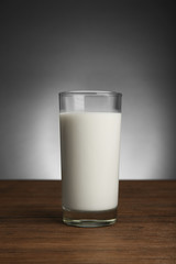Glass of milk on table on dark background
