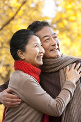 Fototapeta premium Senior couple embracing and surrounded by Autumn trees