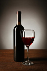 Wine in glass and in bottle on table on dark background