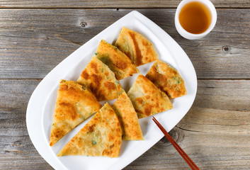 Fried Asian pancakes with tea in white bowl on rustic wood