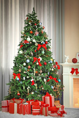 Fototapeta na wymiar Christmas tree with presents near the fireplace in a room