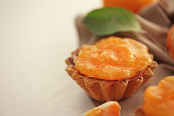 Sweet cakes with tangerines on table, close up