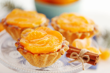 Sweet cakes with tangerines on plate, close up