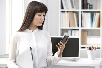 Young businesswoman with smart phone in the office