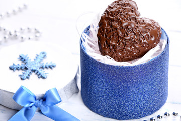 Chocolate heart in a gift box with a bow on a light wooden background
