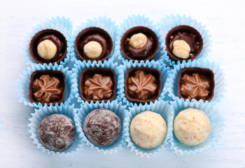 Set of chocolate candies on a light wooden background, close up