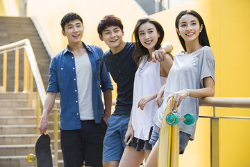 Happy young friends holding skateboards standing together 