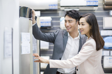 Young couple buying air conditioner in electronics store