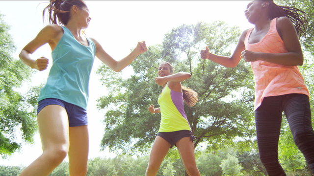 Young happy multi ethnic American females kickboxing to keep fit in park