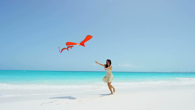 Beautiful young ethnic Asian Chinese girl with red kite on beach 